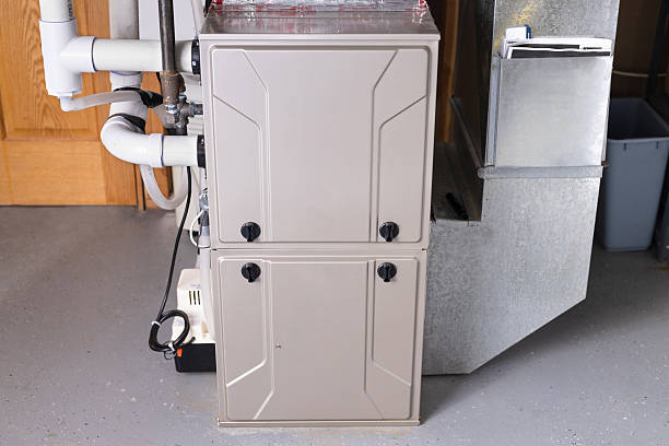 Beige high-efficiency gas furnace with PVC venting, condensate pump and metal ductwork installed in a utility space